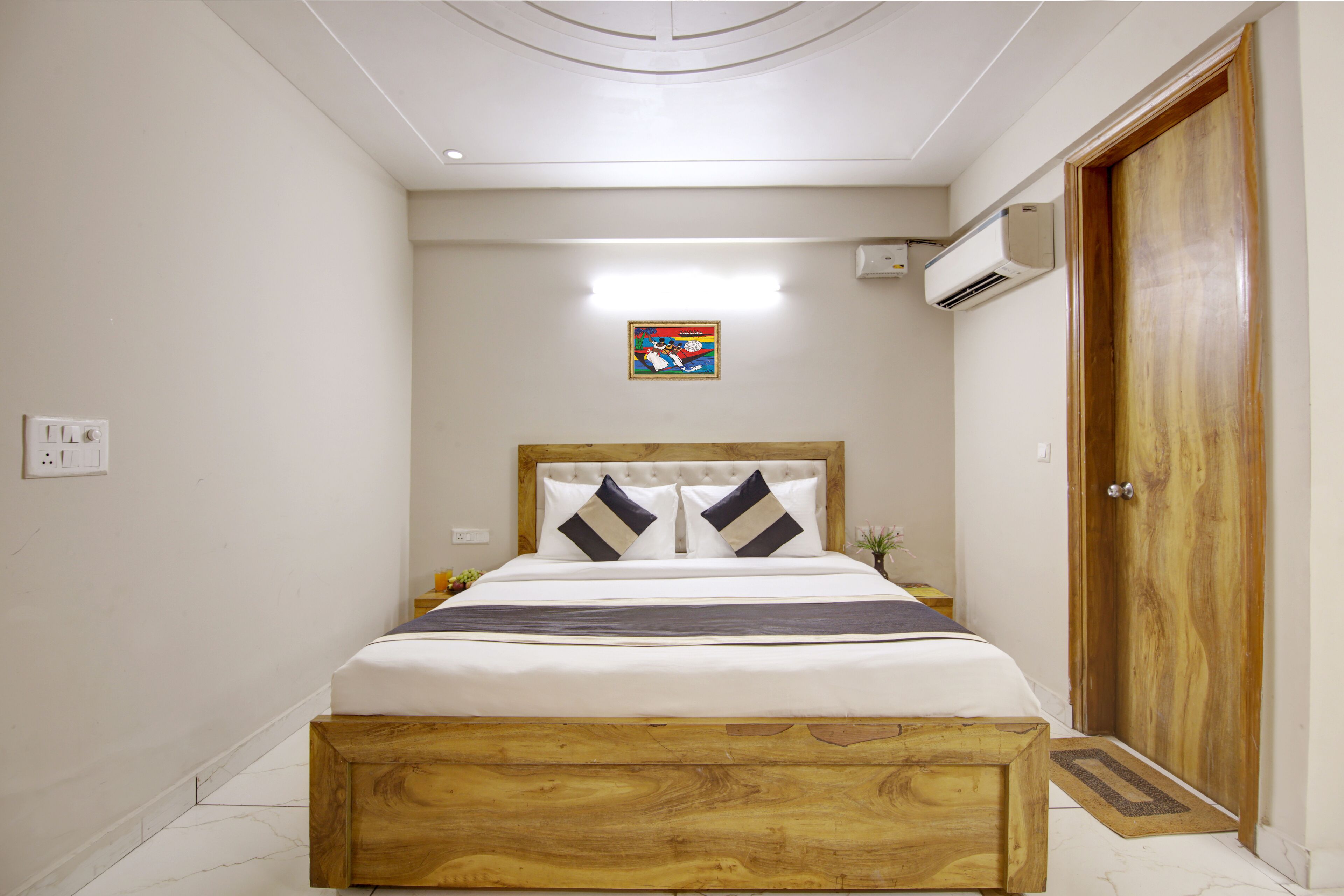 A bedroom with a wooden bed frame, a bedside table, a nightstand, and a door.