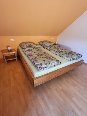 Una cama individual con colcha estampada en una habitación con suelo de madera y techo inclinado.