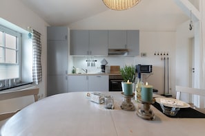 A modern kitchen with grey cabinets, a dining table with candles, and a window with blinds.