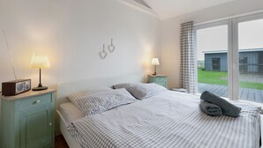 Un dormitorio con una cama, dos mesitas de noche con lámparas, una radio y vistas al exterior.