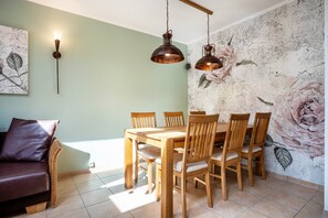 A dining area with a wooden table and chairs, a wall-mounted light fixture, and a floral mural.
