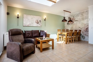 A living room with a sofa, coffee table, and dining area with chairs and a table.