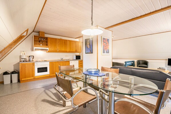 Una cocina moderna con armarios de madera, una mesa de comedor de vidrio y un horno empotrado.