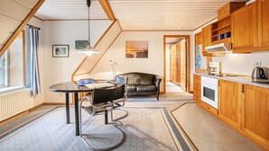 Eine moderne Küche mit Holzausstattung, ein Essbereich mit Tisch und Stühlen sowie ein Blick ins Freie durch ein Fenster.