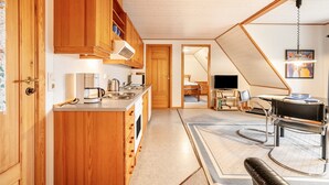 Eine Küche mit Holzausstattung, einer Kaffeemaschine und einem Essbereich mit Tisch und Stühlen.