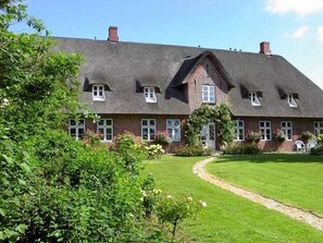 Une grande maison en briques, dotée d’un toit à forte pente, de nombreuses fenêtres et d’une pelouse bien entretenue.