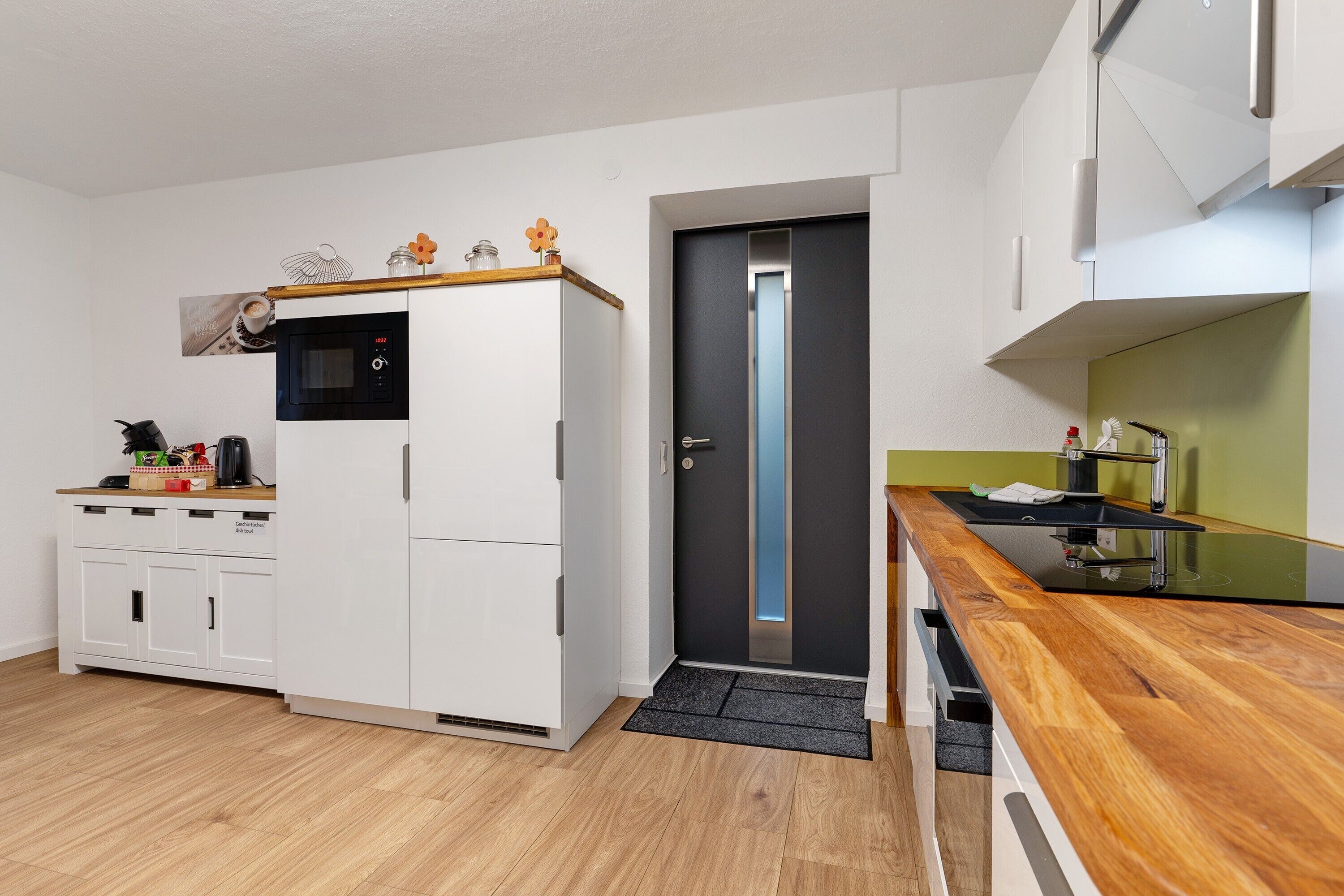 A compact kitchen with a microwave, refrigerator, and wooden countertop.