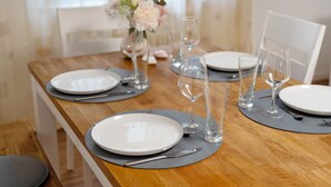 A dining table set with plates, cutlery, and glasses, with a vase of flowers in the background. - Holiday Apartment 'Fewo unter der Kirche' with Wi-Fi (Herbolzheim)