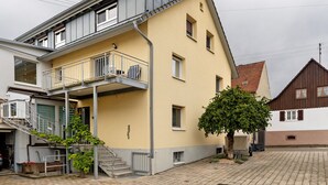 A two-story building with a balcony, a staircase, and a tree in front. - Holiday Apartment 'Fewo unter der Kirche' with Wi-Fi (Herbolzheim)