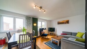 Una sala de estar moderna con comedor, sofá, televisor y ventana con vistas.