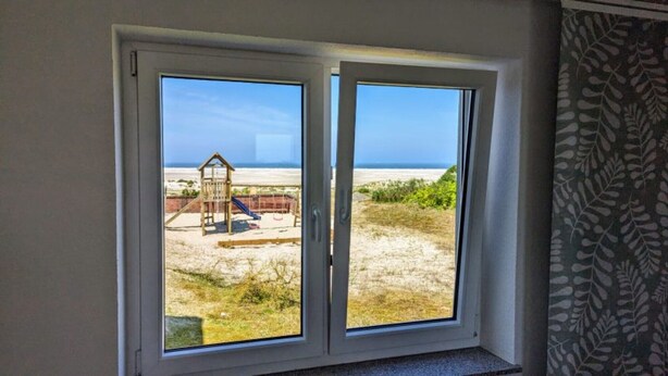 Una habitación con un amplio ventanal corredero que da a una vista de la playa.