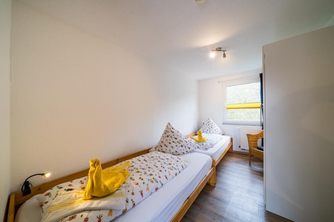 A room with two single beds, a window with a view, a chair, and a radiator.