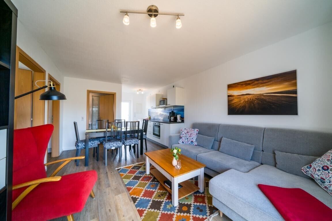 Un salon moderne comprenant un canapé, une table basse et un coin repas avec des chaises et une table.