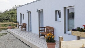 Un edificio de fachada blanca, con bancos de madera y plantas en macetas.