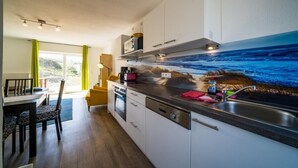 A modern kitchen with a large island, built-in microwave, and a view of the ocean through a mural.
