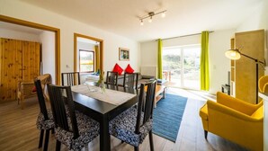 A dining area with a table, chairs, and a yellow armchair.
