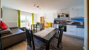 A modern kitchen with white cabinets, a microwave, and a dining area with a table and chairs.