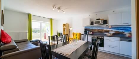 A modern kitchen with white cabinets, a microwave, and a dining area with a table and chairs.
