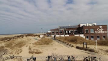 Un edificio con un cartello che riporta 'Café Sturmeck' su una spiaggia sabbiosa, con biciclette parcheggiate davanti.