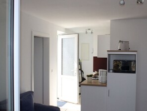A compact kitchen with a microwave, coffee maker, and a small plant on the counter.