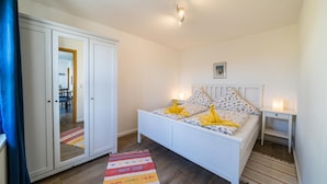 Une chambre à coucher avec un lit, des tables de chevet, une armoire et un miroir.