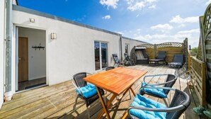 Eine Holzterrasse mit Tisch und Stühlen, einer Tür und einem überdachten Sitzbereich.