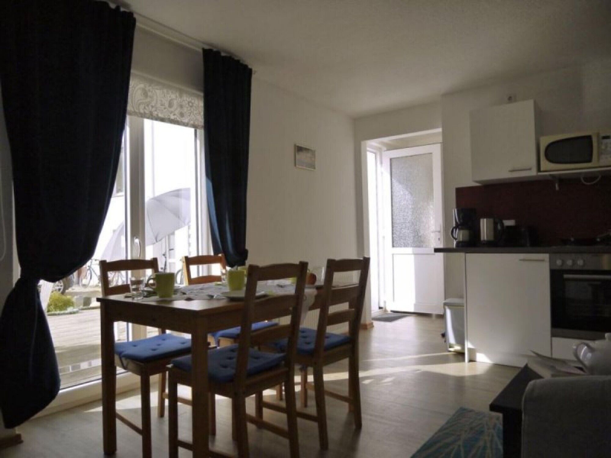 Un comedor con mesa y sillas, una cocina con electrodomésticos y una puerta que da al exterior.