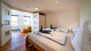 A bedroom with two beds, a wooden floor, a window, and a door.