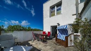 A patio with outdoor furniture, a white building, and a clear blue sky.