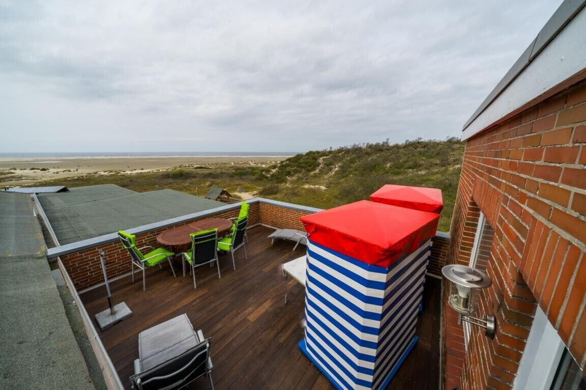 Eine Dachterrasse mit Blick auf den Strand, eine Ziegelwand und eine gestreifte Säule.