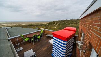 Eine Dachterrasse mit Blick auf den Strand, eine Ziegelwand und eine gestreifte Säule.