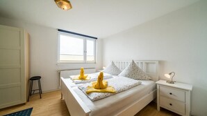 Ein Schlafzimmer mit einem Bett, einem Nachttisch, einem Fenster und einer Heizung.