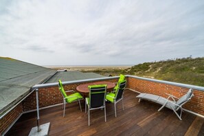 Une terrasse sur le toit avec un mur en briques, une table ronde entourée de chaises et un fauteuil de relaxation.