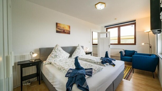 Een slaapkamer met een bed, nachtkastjes, een bureau, een stoel en een raam.