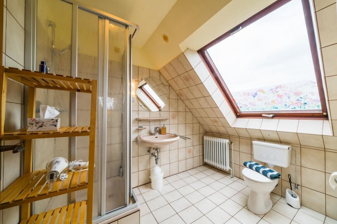 Une petite salle de bain compacte, équipée d’une douche, d’un lavabo, de toilettes et d’un puits de lumière.