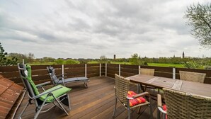 An outdoor deck with a table and chairs, surrounded by a wooden fence. - Apartment 'Olde Toornblick' with Balcony and Wi-Fi (Borkum)