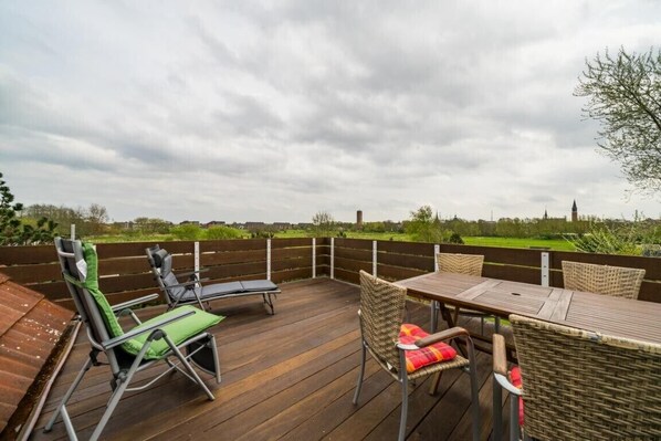 An outdoor deck with a table and chairs, surrounded by a wooden fence.