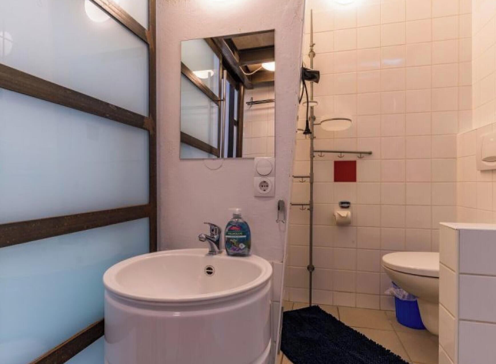 Ein Badezimmer mit Waschbecken, Spiegel, Toilette und Dusche.