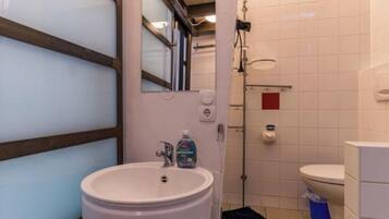 Ein Badezimmer mit Waschbecken, Spiegel, Toilette und Dusche.