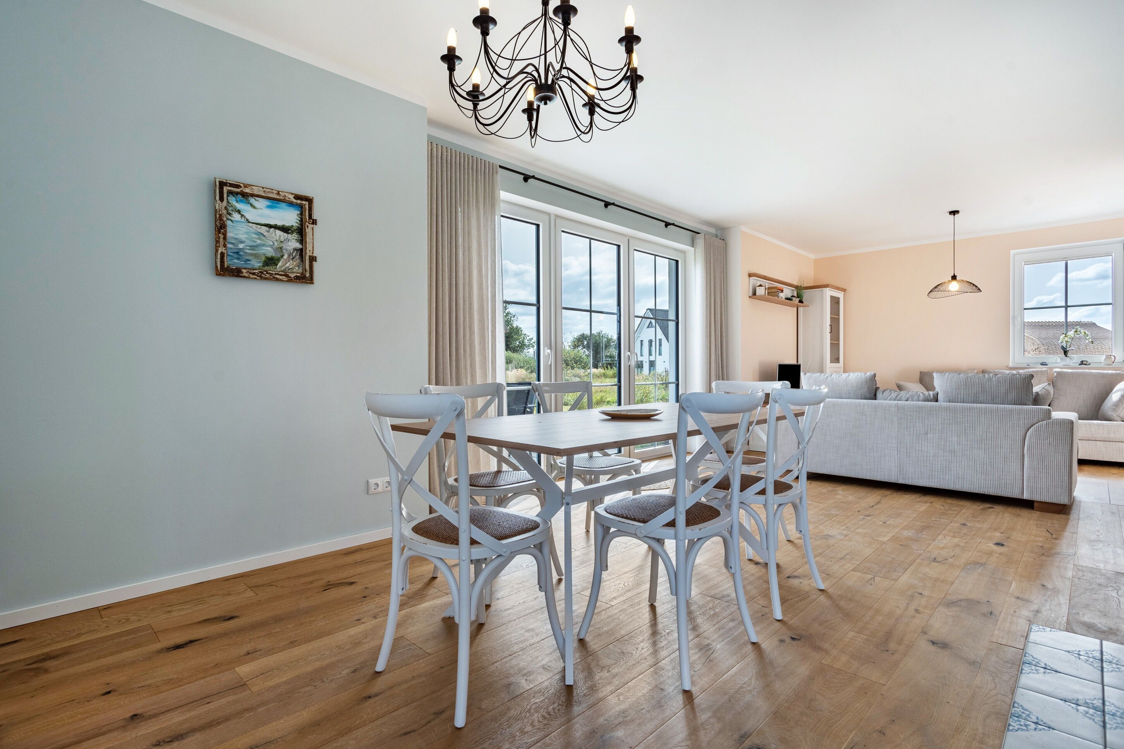 Un coin repas comprenant une table et des chaises, un lustre et un tableau accroché au mur.