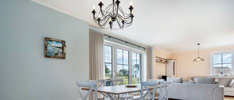 Un coin repas comprenant une table et des chaises, un lustre et un tableau accroché au mur.