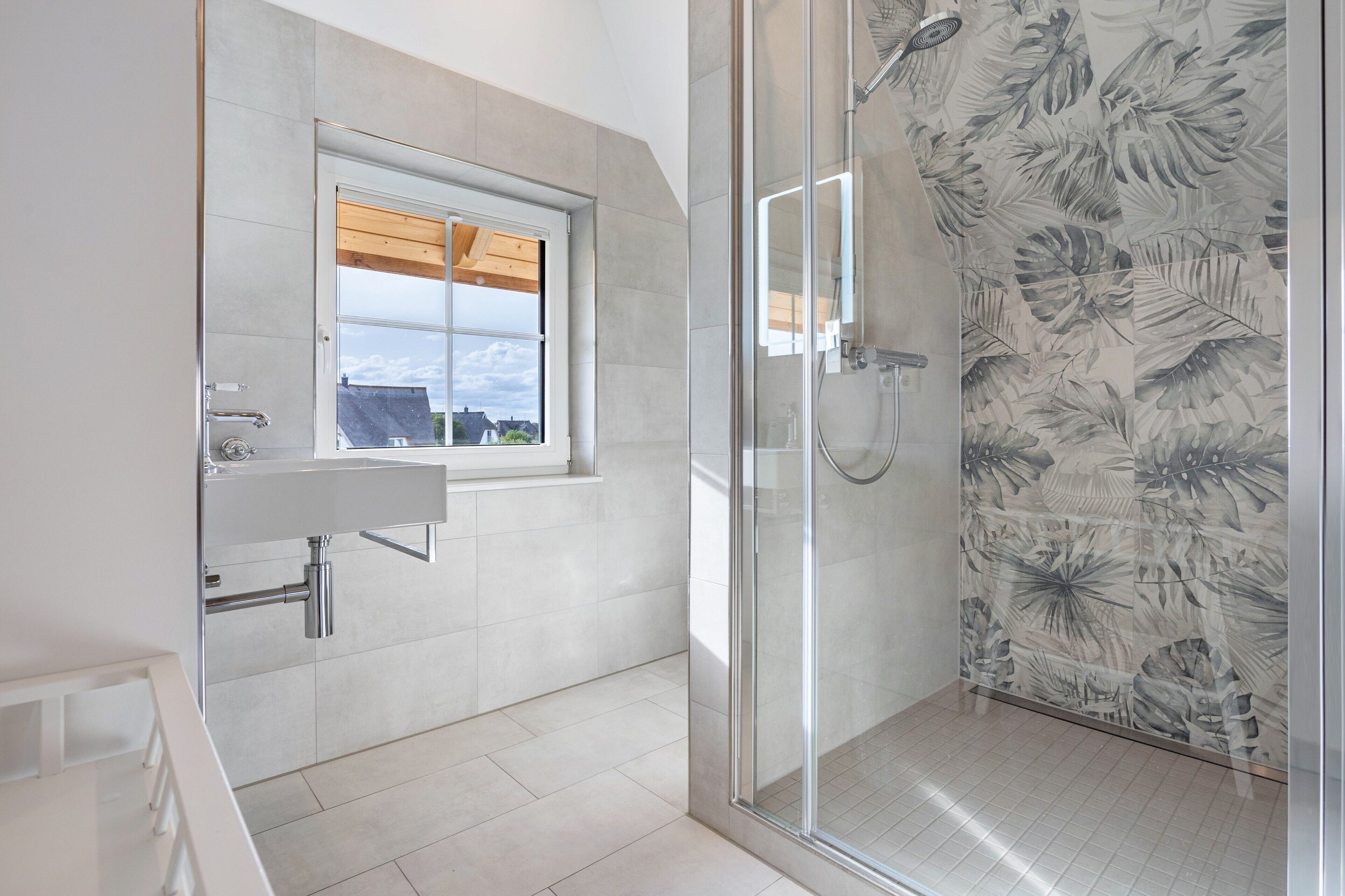 Un baño moderno con ducha, ventana y lavamanos.