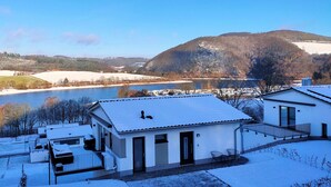 A residential area with houses, a river, and a mountain in the background. - Holiday Home 'Christa' with Lake View, Private Terrace and Wi-Fi (Diemelsee)