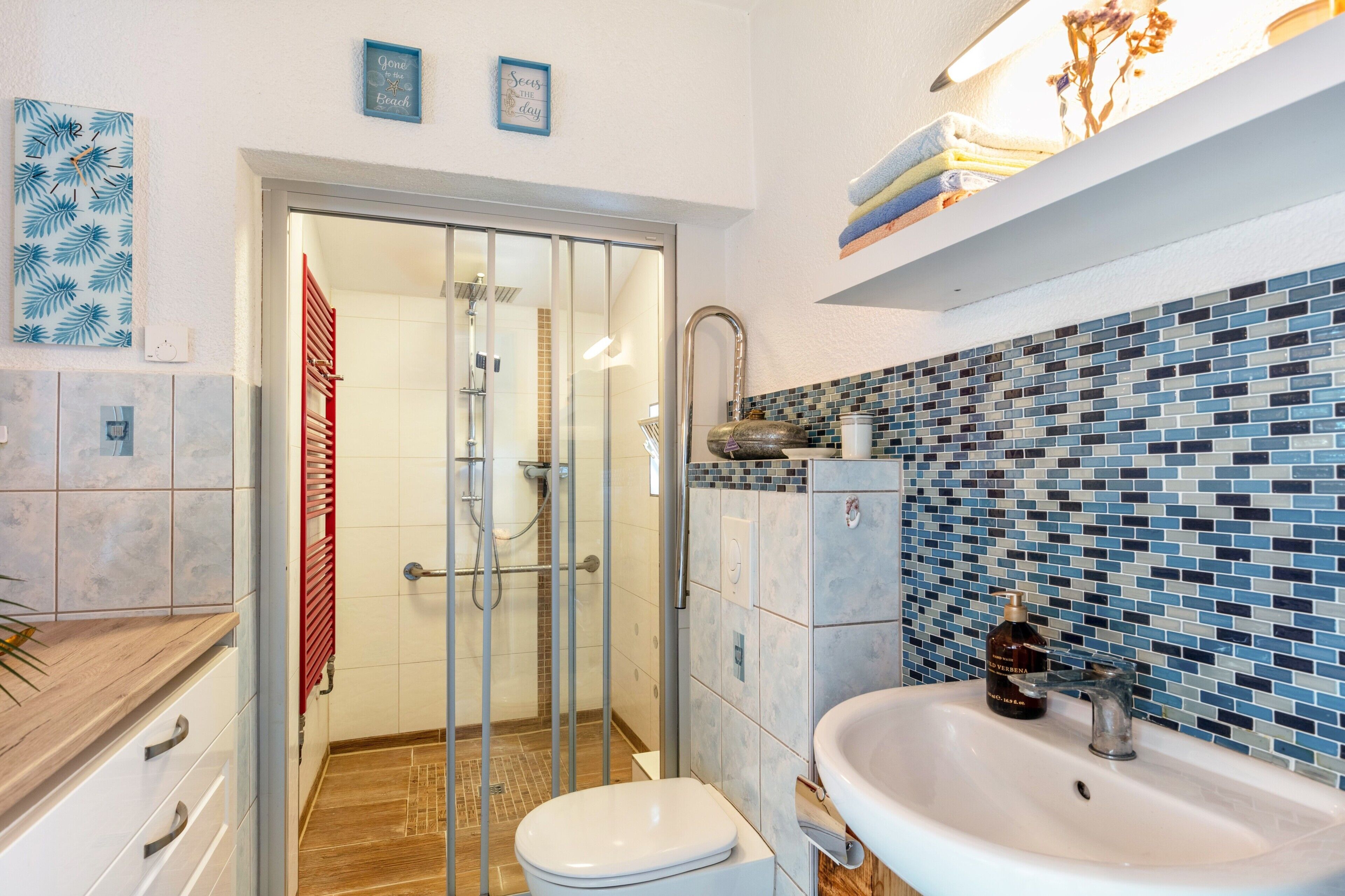 Ein Badezimmer mit Dusche, Toilette, Waschbecken und gefliesten Wänden.
