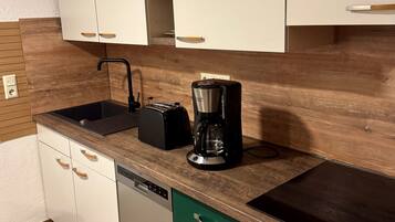 Une cuisine moderne avec des armoires blanches, un pare-feu en bois, une machine à café, un lave-vaisselle et une cuisinière.
