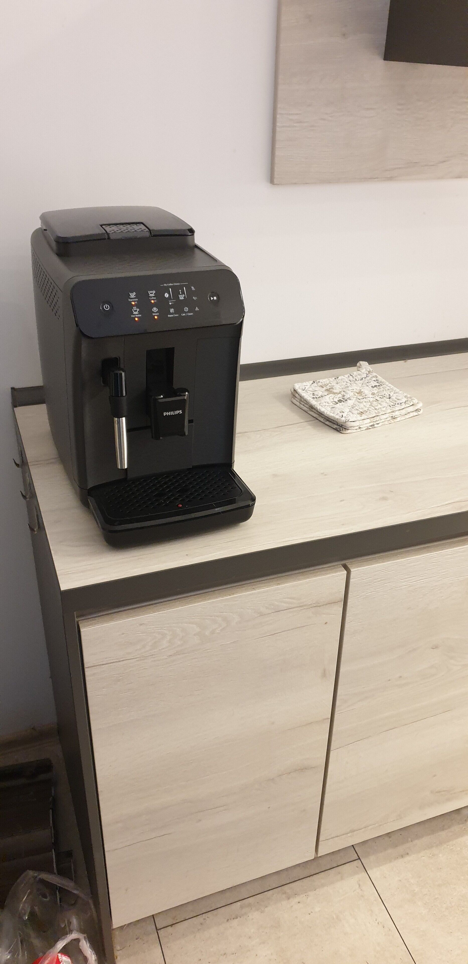 A coffee machine on a wooden counter with a small tray and a patterned cloth.