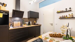 A modern kitchen with a built-in oven, microwave, and stove, wooden countertop, and a small herb garden on the table.