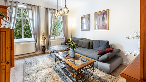 A living room with a sofa, a coffee table, a fireplace, and a window with curtains.
