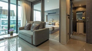 Uma sala de estar moderna com um sofá, uma mesa de jantar com planta em vaso e vista para um horizonte urbano através de grandes janelas.