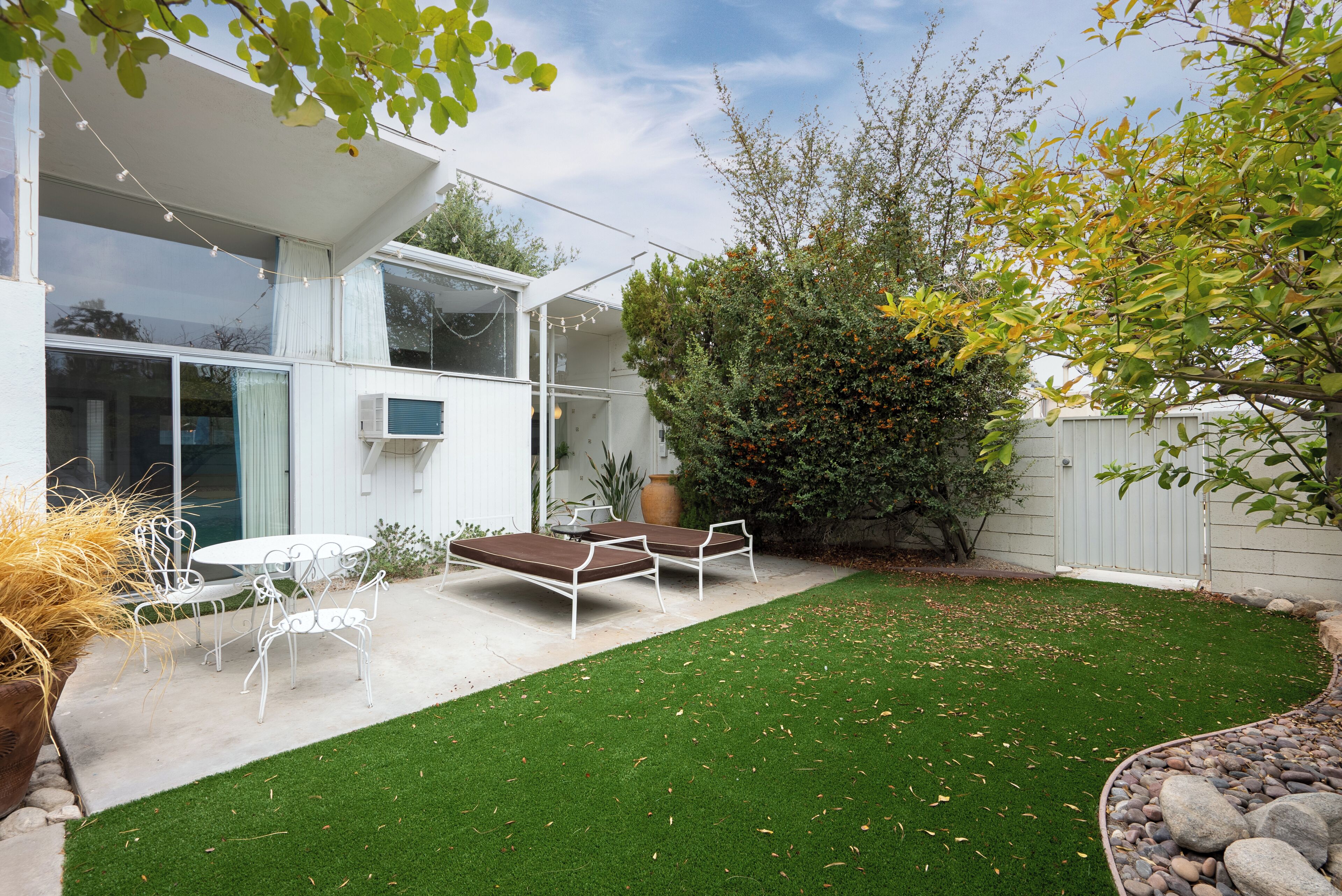 A modern house with a patio, outdoor furniture, and a well-maintained lawn.